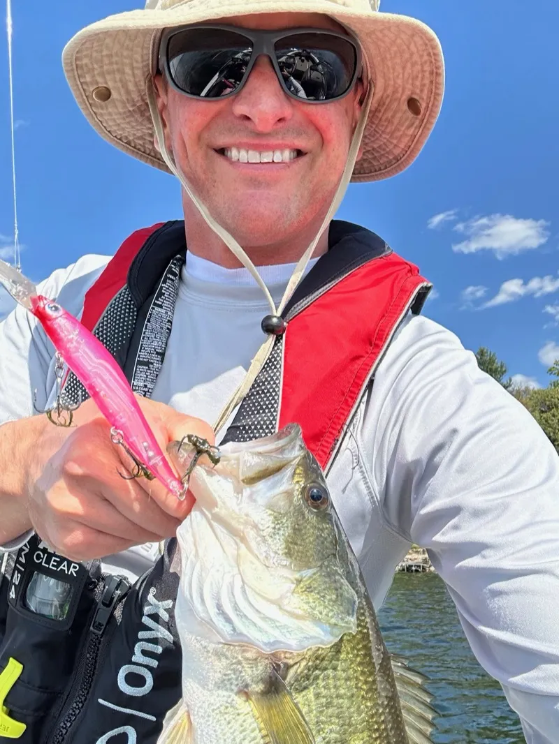 Angler holding a largemouth bass caught on a jerkbait at a rocky point